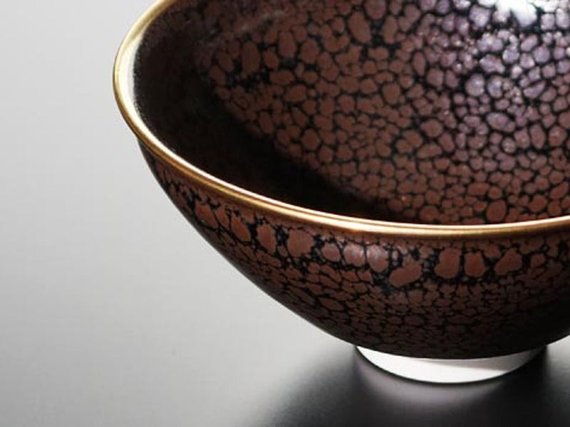 Oil-spot tenmoku tea bowl with a gold rim, Arita ware, silver droplets scattered across a black glaze